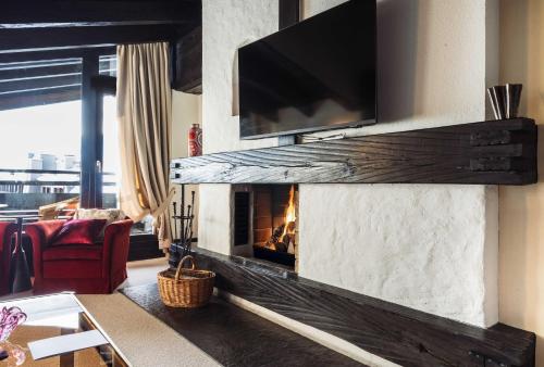 a living room with a fireplace with a tv above it at A-ROSA Hotel Thurnher's Alpenhof in Zürs am Arlberg