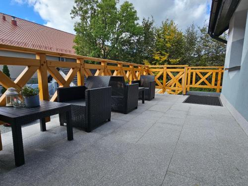 a patio with chairs and tables and a wooden fence at Richmount Apartamenty Karpacz in Karpacz