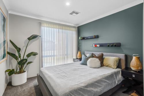 a bedroom with a bed with a blue wall at Amberton Beachs Little Paradise By Swan Bnb in Alkimos