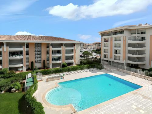 - une vue sur la piscine en face de deux immeubles d'appartements dans l'établissement Appartement confortable à Fréjus, 35 m² avec balcon agréable, à Fréjus