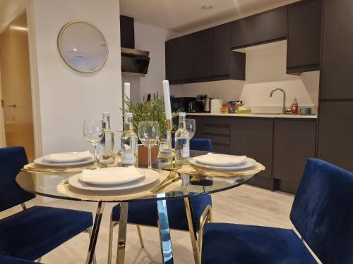 a dining room table with wine glasses and blue chairs at 2 Bed Affordable Luxury City Centre Flat in Birmingham