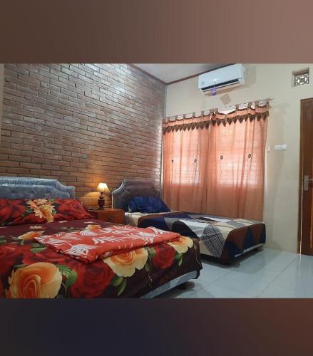a bedroom with two beds and a brick wall at Homestay Durohman Borobudur in Mendut