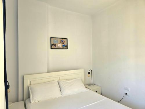 a white bedroom with a bed and a picture on the wall at Sunny Beach Penthouse - 216 in Durrës