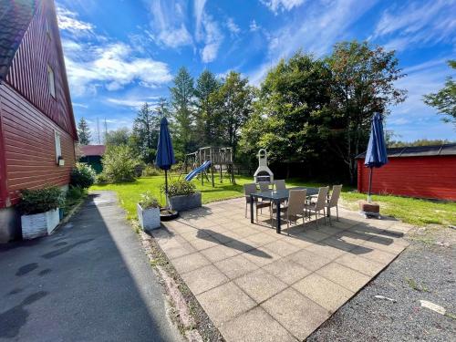 eine Terrasse mit einem Tisch, Stühlen und Sonnenschirmen in der Unterkunft HIRSCH Gretel Ferienhaus - Garten mit Grill - Wald in Altenau