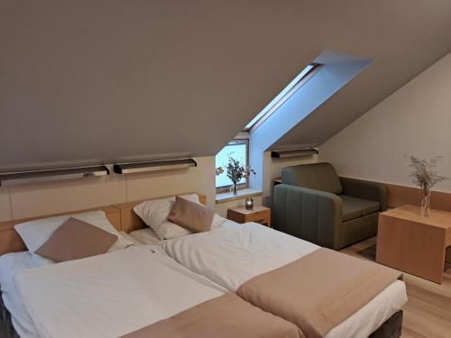 a attic bedroom with a bed and a chair at Hotel Kolna - darmowy parking, basen w cenie in Krakow
