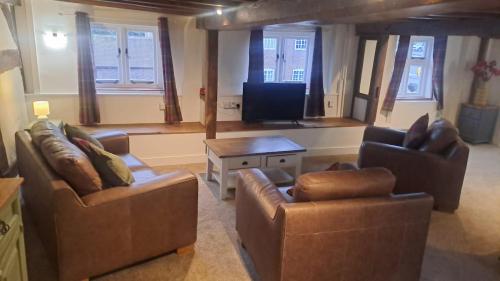 ein Wohnzimmer mit zwei Sofas und einem Fernseher in der Unterkunft Charming Four Person Malthouse Apartment in Much Wenlock