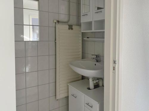 a white bathroom with a sink and a mirror at Boerderijhuisje 22 - Landelijk logeren bij Sneek in Loënga