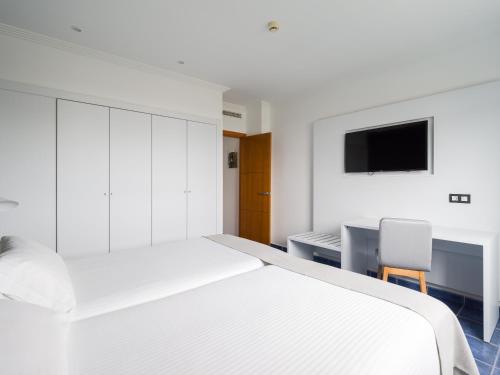 a white bedroom with two beds and a tv at Hotel Mirador Papagayo by LIVVO in Playa Blanca