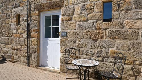 a table and two chairs in front of a stone building at St Hildas Complex in Hinderwell