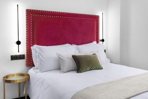 a bedroom with a white bed with a red headboard at Hotel Aptos Alejandra Home by Maxi Hoteles in Granada