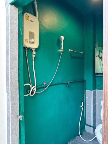 a bathroom with a green wall and a toilet at Shared Room Megun in Ban Bang Phlat