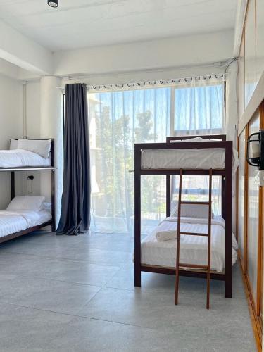 a bedroom with two bunk beds and a large window at Shared Room Megun in Ban Bang Phlat