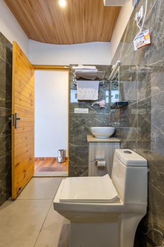 a bathroom with a toilet and a sink at The Deodar Stays in Kanatal