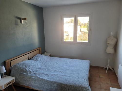 sypialnia z niebieskim łóżkiem i oknem w obiekcie Maison individuelle 90m2 avec véranda et piscine w mieście Roquemaure