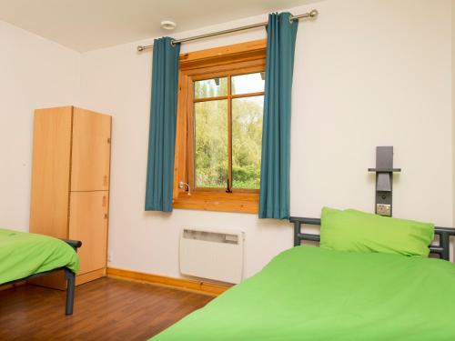 a bedroom with two green beds and a window at YHA London Lee Valley in Cheshunt