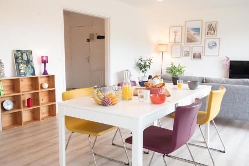 - une table à manger blanche avec des chaises jaunes dans le salon dans l'établissement Beau T3 Centre-ville & Plage à pied par Groom, à Larmor-Plage