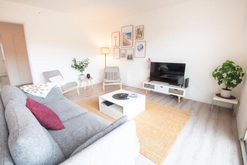 un salon avec un canapé gris et une télévision dans l'établissement Beau T3 Centre-ville & Plage à pied par Groom, à Larmor-Plage