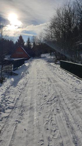 a snow covered road with a barn in the background at Tkalcovna U Zlatého potoka in Dobřany