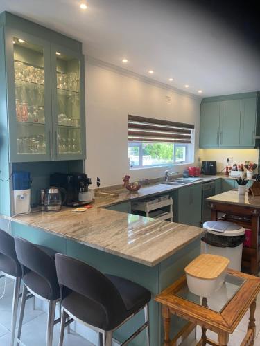 a kitchen with green cabinets and a large island with bar stools at 8 Sleeper, 4 Bedroom Home in Franschhoek in Franschhoek