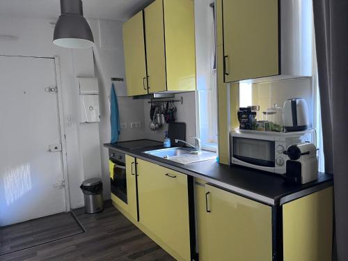 une cuisine avec des armoires jaunes et un micro-ondes dans l'établissement Paris Saint-Paul, à Paris