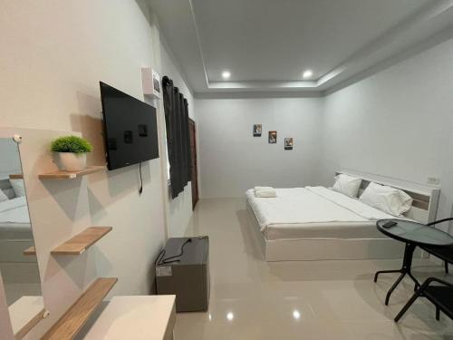 a white room with a bed and a tv in it at บ้านพูลทรัพย์ที่พัก POONSUB TEEPAk in Phibun Mangsahan