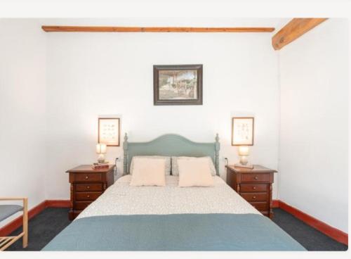 Un dormitorio con una cama azul y dos mesitas de noche. en Ensueño Alojamiento Turístico, en Alcublas