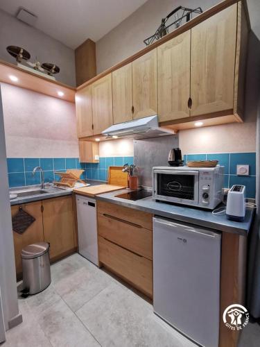 a kitchen with wooden cabinets and a microwave at Domaine de Stony - Eco-Gîtes et Vignoble in La Peyrade