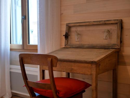 a wooden desk with a red chair next to a window at Domaine de Stony - Eco-Gîtes et Vignoble in La Peyrade