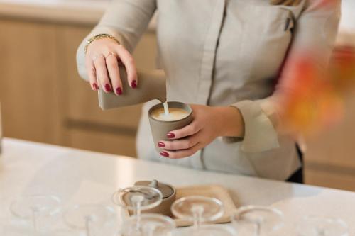 a woman holding a cup of coffee on a counter at Hotel Bommelje in Domburg