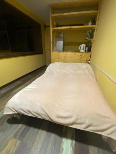 a bed in a room with a white blanket at Cabaña con Vista Bosque y Río in Villa Cerro Castillo