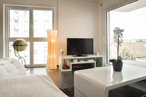 a living room with a television and a white couch at Neubau Stuttgart Messe Airport in Leinfelden-Echterdingen