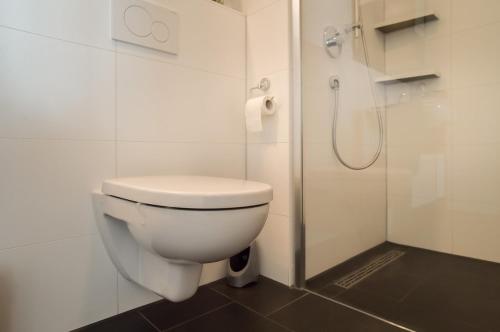 a white bathroom with a toilet and a shower at Neubau Stuttgart Messe Airport in Leinfelden-Echterdingen