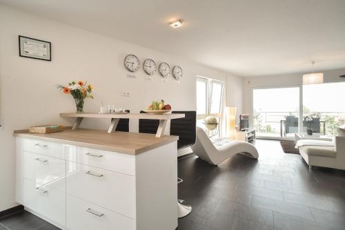 a kitchen with white cabinets and a living room at Neubau Stuttgart Messe Airport in Leinfelden-Echterdingen