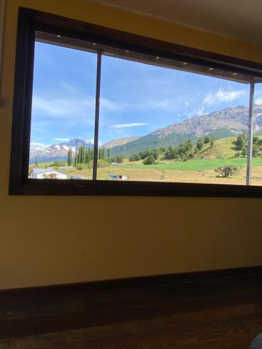 a window with a view of a field and mountains at Cabaña con Vista Bosque y Río in Villa Cerro Castillo