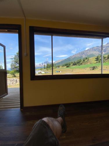 a person laying on the floor looking out of a window at Cabaña con Vista Bosque y Río in Villa Cerro Castillo