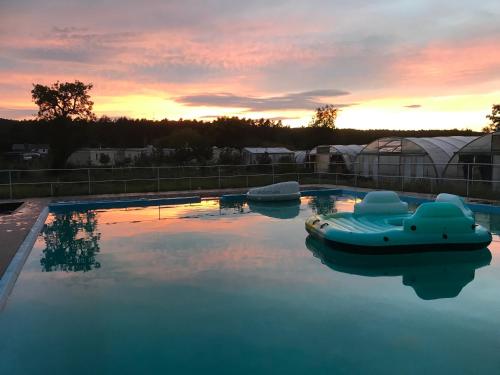 a pool with a boat in the water at sunset at Moderne Ferienwohnungen mit Terrasse, Pool, Wallbox & Spielplatz in den Götzer Bergen - ideal für Ihren Berlin-Besuch und auch für Gruppen bis zu 40 Personen geeignet in Groß Kreutz