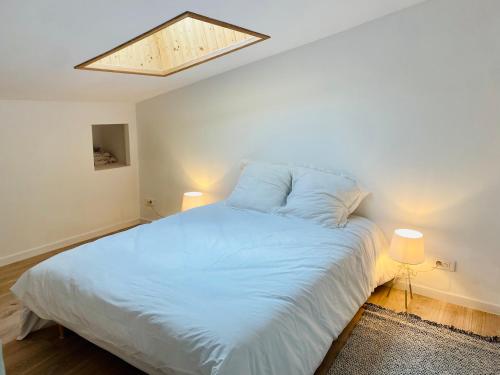 - une chambre avec un grand lit blanc et une lucarne dans l'établissement Joli duplex en montagne, à Risoul