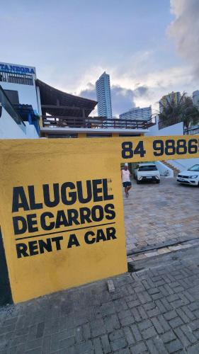 a yellow sign that readsuelraviolet dangerous rent a car at Mirassol Flats in Natal