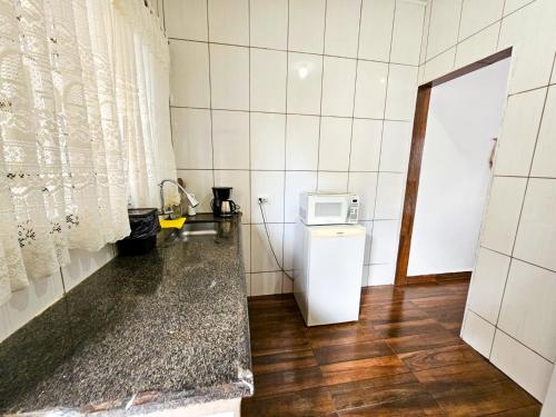 a small kitchen with a microwave and a refrigerator at Casa perto do Parque dos Saltos - Brotas - Casa 3 in Brotas