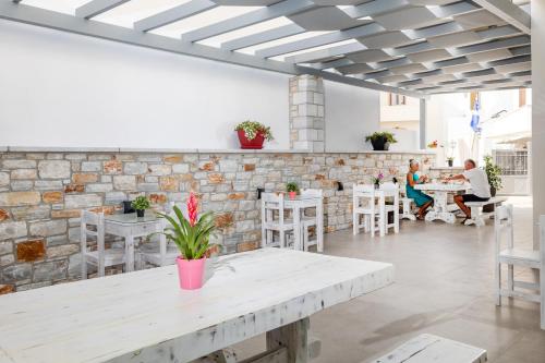 a restaurant with white tables and chairs and a brick wall at Katerina Roza Studios - Heartfelt Hospitality in the City in Naxos Chora