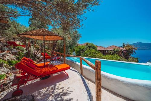 a beach chair with an umbrella next to a swimming pool at Fidanka Hotel in Kalkan