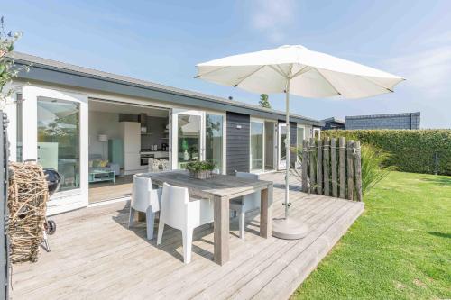 a wooden deck with a table and an umbrella at Buitenplaats Oudendijke in Ellemeet