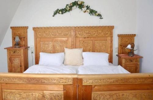 a large wooden bed with white sheets and a wreath on it at Apartment Grattschlössl in Sankt Johann in Tirol