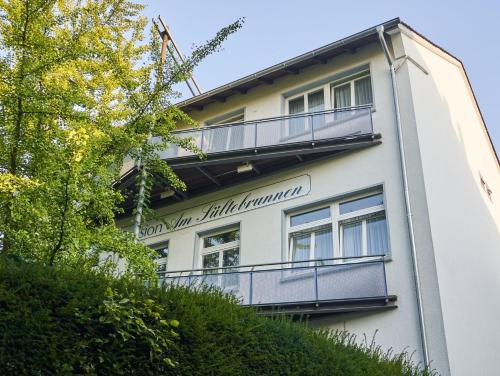 a white building with a balcony on the side at Pension Am Sültebrunnen in Bad Oeynhausen
