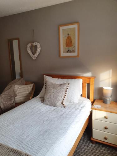 a bedroom with a bed with white sheets and a table at Apple Blossom Guesthouse in Rempstone