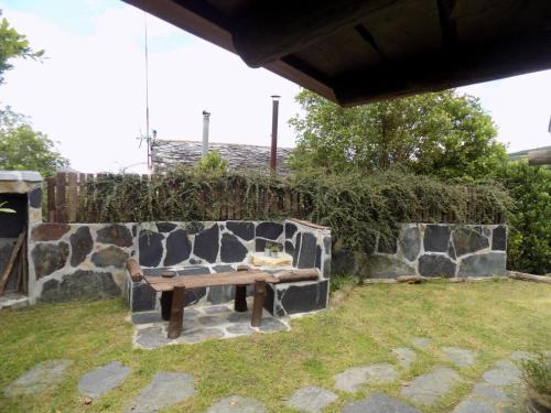 a wooden bench sitting next to a stone wall at Cabaña Bioxana in Molejón
