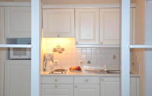 a kitchen with white cabinets and a bowl of fruit at Apartment Grattschlössl in Sankt Johann in Tirol