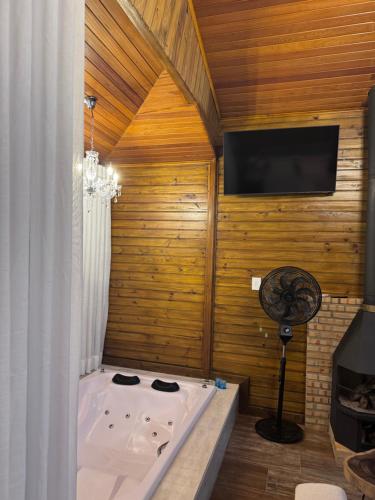 a bath tub in a room with a flat screen tv at Pousada Alto Colina - Chalé Quero-quero in Venda Nova do Imigrante