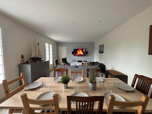 une salle à manger avec une table et des chaises en bois dans l'établissement La Fromagerie Maison lumineuse et spacieuse beau séjour 5 ch 2 wc 1 sdb grand jardin clos 5mn à pied commerces 10 mn plage Omaha Beach proche plages du débarquement, à Trévières