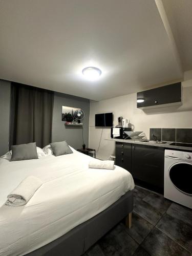 une chambre avec un grand lit blanc et une cuisine dans l'établissement La Clé Studio Proche Port - Gare - Wifi, à Toulon